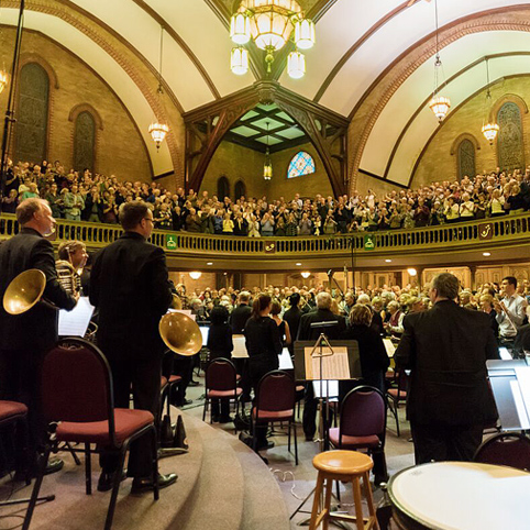 orchestra standing up in front of audience applauding