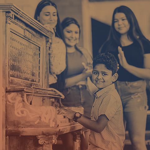 A boy from London, Ontario sitting and playing at a piano with three females listening and clapping